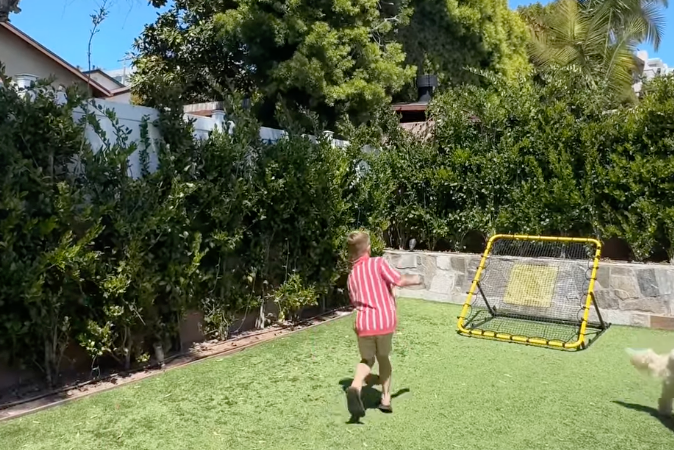 Kid playing catch against a rebounder net